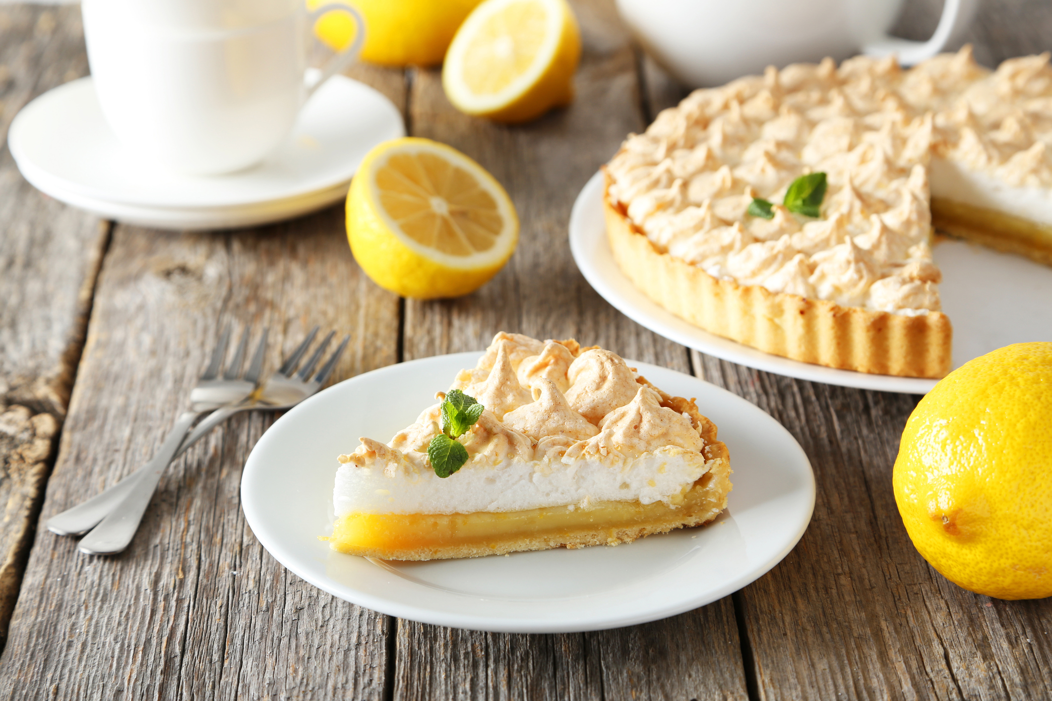 Lemon meringue pie on plate on grey wooden background